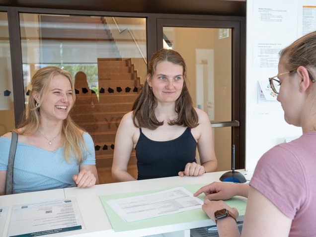 © MUL Zwei Studentinnen am Infopoint; eine Mitarbeiterin erklärt die Anmeldeunterlagen.