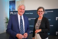 Zwei Personen in formeller Kleidung vor einem Montanuniversität‑Leoben‑Backdrop; links blauer Anzug mit Krawatte, rechts schwarzer Blazer.