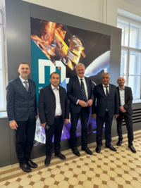 Gruppenfoto: Delegation der Navoi State University of Mining and Technologies zu Besuch an der Montanuniversität Leoben, Innenaufnahme vor MUL-Wand.