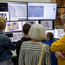 Besucher vor vielen Bildschirmen im Labor.