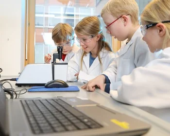 Kinder in Laborkitteln beim Experimentieren.