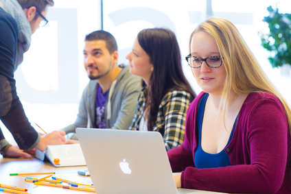 Mehrere Studierende sitzen an einem Tisch, lernen und beraten sich.