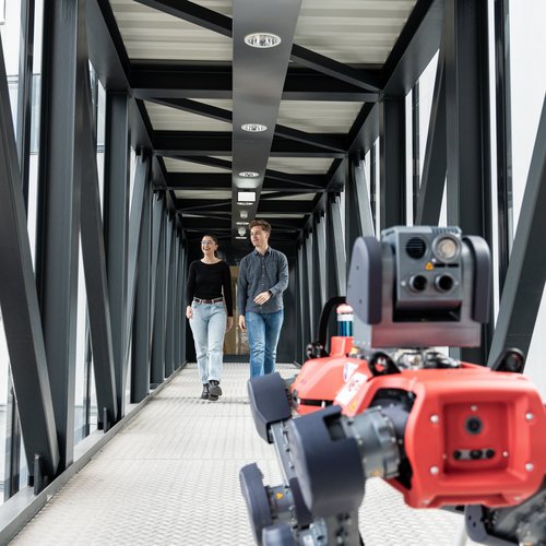 Zwei Studenten im Gang mit einem Roboterhund.