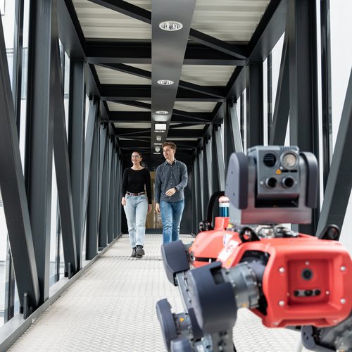 Zwei Studenten im Gang mit einem Roboterhund.