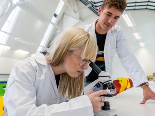 © Science Garden Zwei Studenten in einem Labor mit einem Mikroskop.