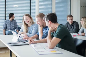 Studierende sitzen in einem Klassenraum, lernen und beraten sich