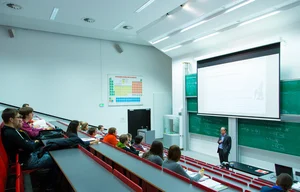 Several people are sitting in a lecture hall.