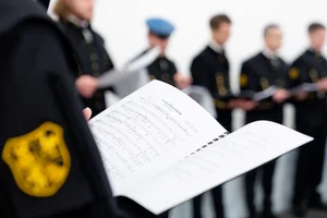 Notenblätter werden von einem Chormitglied gehalten.