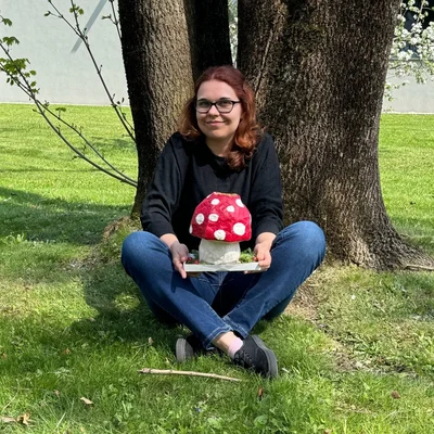 Jessica Michalke posiert unter einem Baum mit einem selbstgebastaltem Pilz aus Pappe