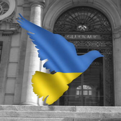 Graphic image of a peace dove in the colors of the Ukrainian flag in front of the main portal of the Montanuniversität 