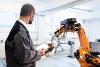 Mann in Werkhalle an Maschine: Faserverbund-Bauteile für die Luft- und Raumfahrt werden zu einem großen Teil Stück für Stück mit einem Wickelroboter hergestellt.
