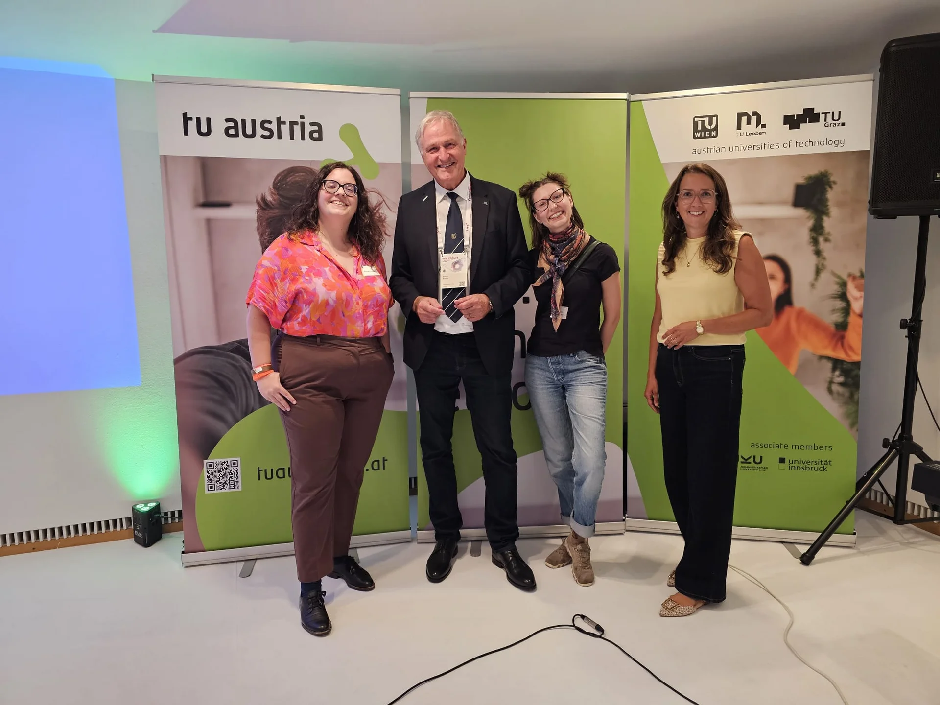 Vertreter*innen der TU Austria posieren bei einer Veranstaltung vor Roll-ups der technischen Universitäten Österreichs.