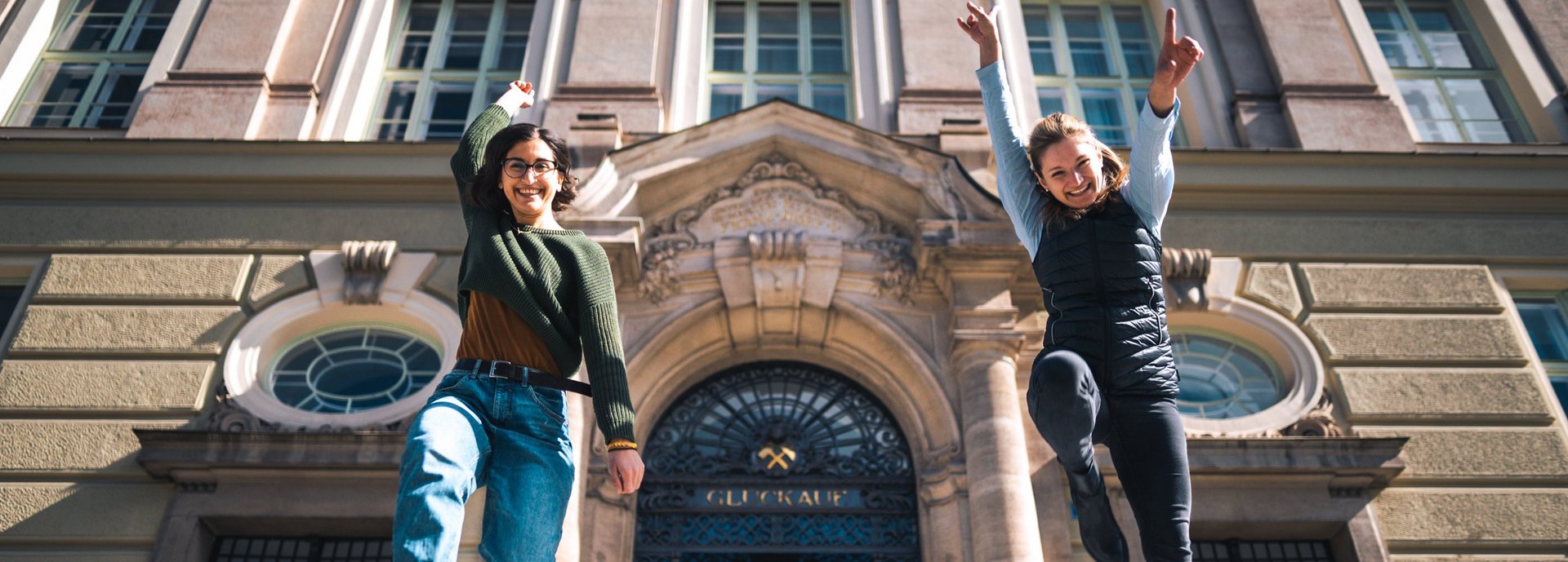 Zwei angehende Studentinnen freuen sich auf ihr Studium vor dem Hauptgebäude der Montanuniversität.