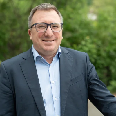 Portraitfoto, Mann mit dunklem Anzug und hellem Hemd, Brille.