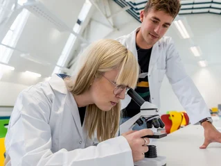 Zwei Studenten in einem Labor mit einem Mikroskop.