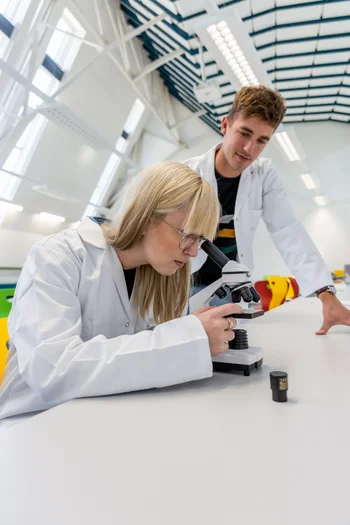 Zwei Studenten in einem Labor mit einem Mikroskop.