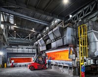Industrielle Aluminiumproduktion im AMAG-Werk Ranshofen: Ein Gabelstapler transportiert Material vor einem glühenden Ofen zur Verarbeitung von Aluminiumlegierungen.
