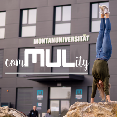 Junge Frau macht einen Handstand vor dem schwarzen Gebäude der Montanuniversität Leoben.