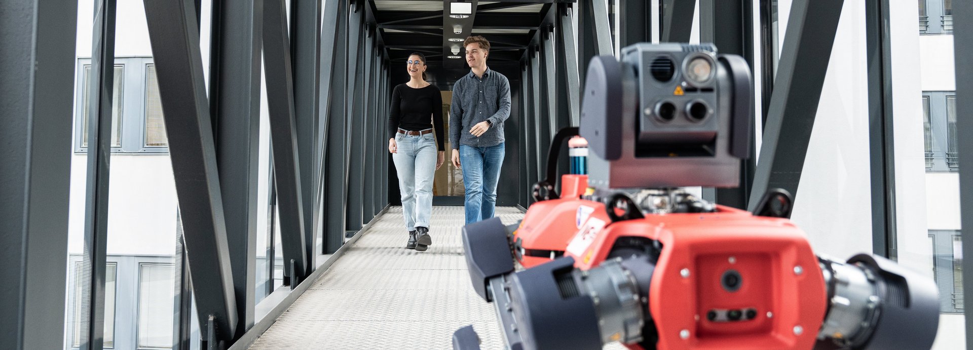Zwei Studenten und ein Roboterhund im Gang der Montanuni.