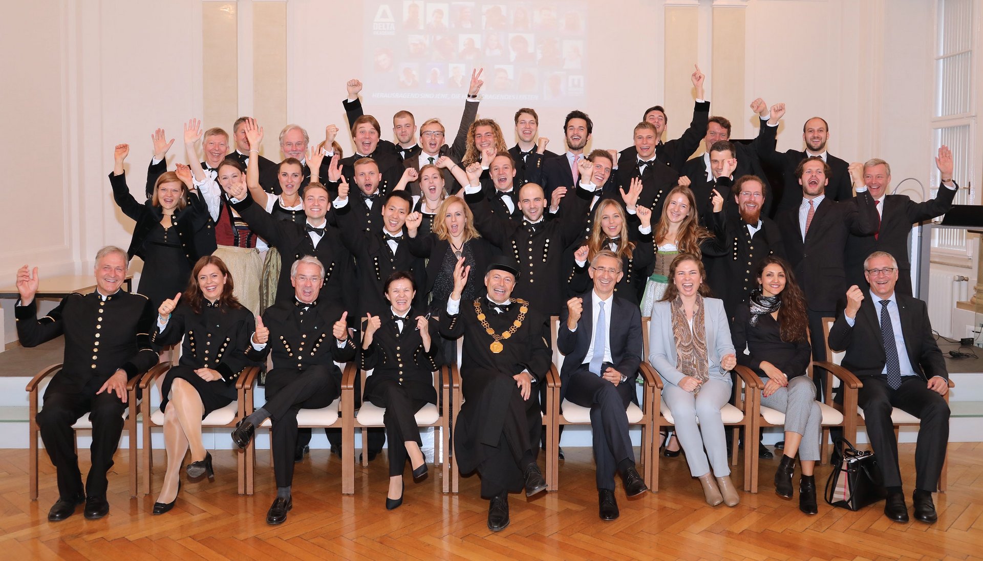 Gruppenfoto, aufgenommen in der Aula der Montanuniversität. Jubelnde Studierende und Ehrengäste feiern die Zertifikats-Verleihung.