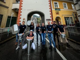 Nove Ponto Nove in front of the Schwammerlturm in Leoben. Photo: © Martin Trieb A group of drummers stands with their instruments in front of the Schwammerlturm tower in Leoben.