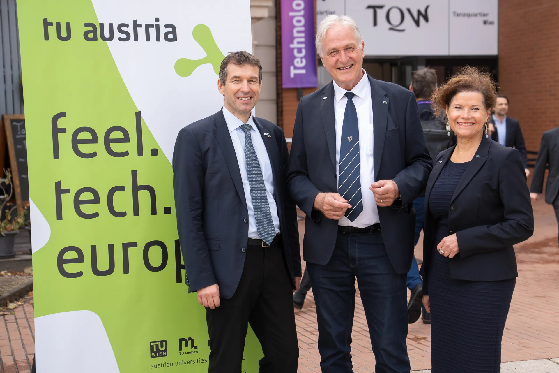 Drei Vertreter*innen der TU Austria bei einer Veranstaltung vor einem Banner mit dem Slogan „feel. tech. europe.“.