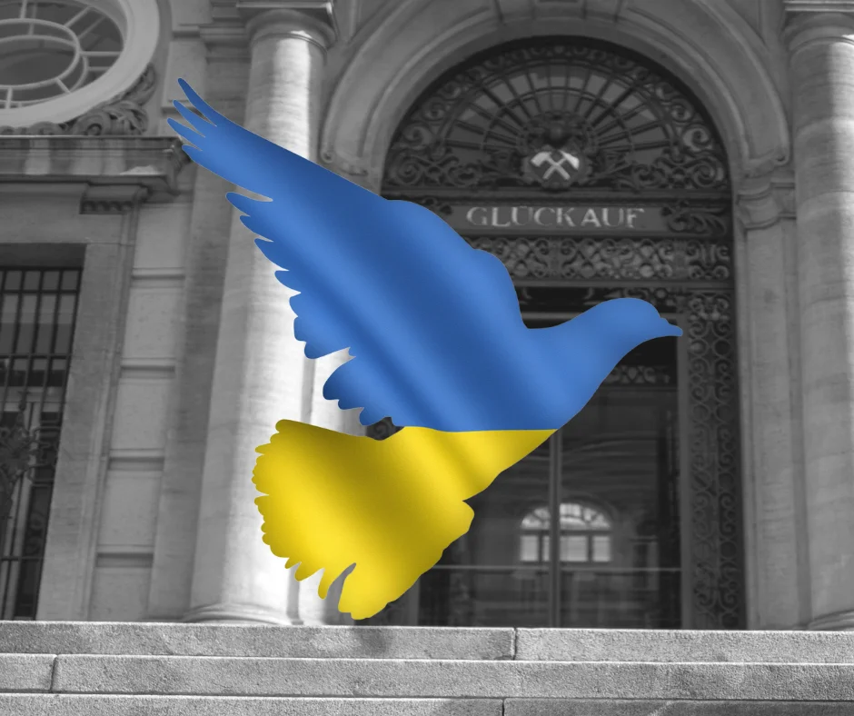 Graphic image of a peace dove in the colors of the Ukrainian flag in front of the main portal of the Montanuniversität