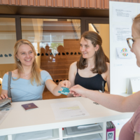 Two young women, around 20 years old, receive the MU ID card to register for the Montanuniversität.