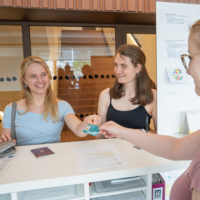 Zwei junge Frauen, um 20 Jahre, bekommen den MU Ausweis zur Anmeldung für die Montanuniversität.