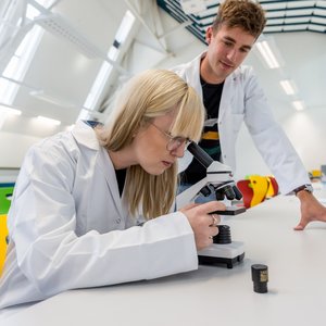 Zwei Studenten in einem Labor mit einem Mikroskop.
