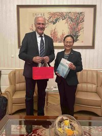 Zwei Personen im schwarzen Hosenanzug in einem Büro, Rektor Peter Moser und die chinesische Botschafterin Qi Mei. 