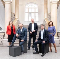The rector and vice-rectors of the Technical University stand side by side in front of the new study centre, all smiling in their official attire. 