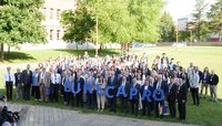 Großes Gruppenfoto im Freien auf einem Campusrasen. In der ersten Reihe halten Teilnehmende große blaue Buchstaben, die „EURECA PRO“ ergeben. Bäume und Hochschulgebäude im Hintergrund, sonniges Wetter.